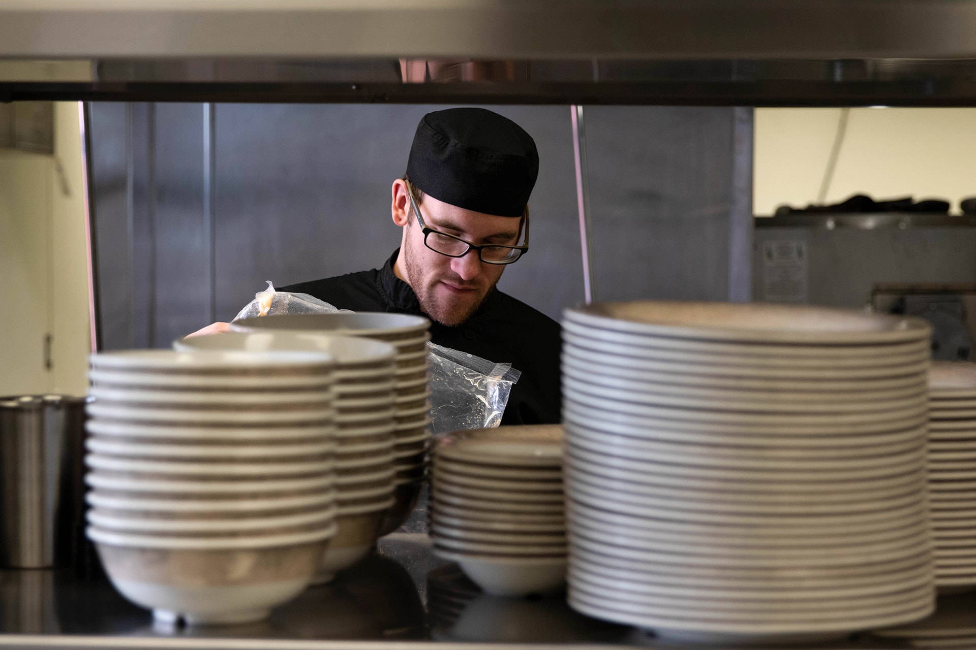 A chef stands behnind stacks of plates